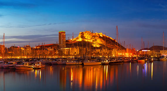 Panorama of port with yachts against cityspace and Castle of Santa Barbara in night  Alicante, Spain