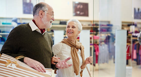 Senior spouses with paperbags talking while shopping in the mall